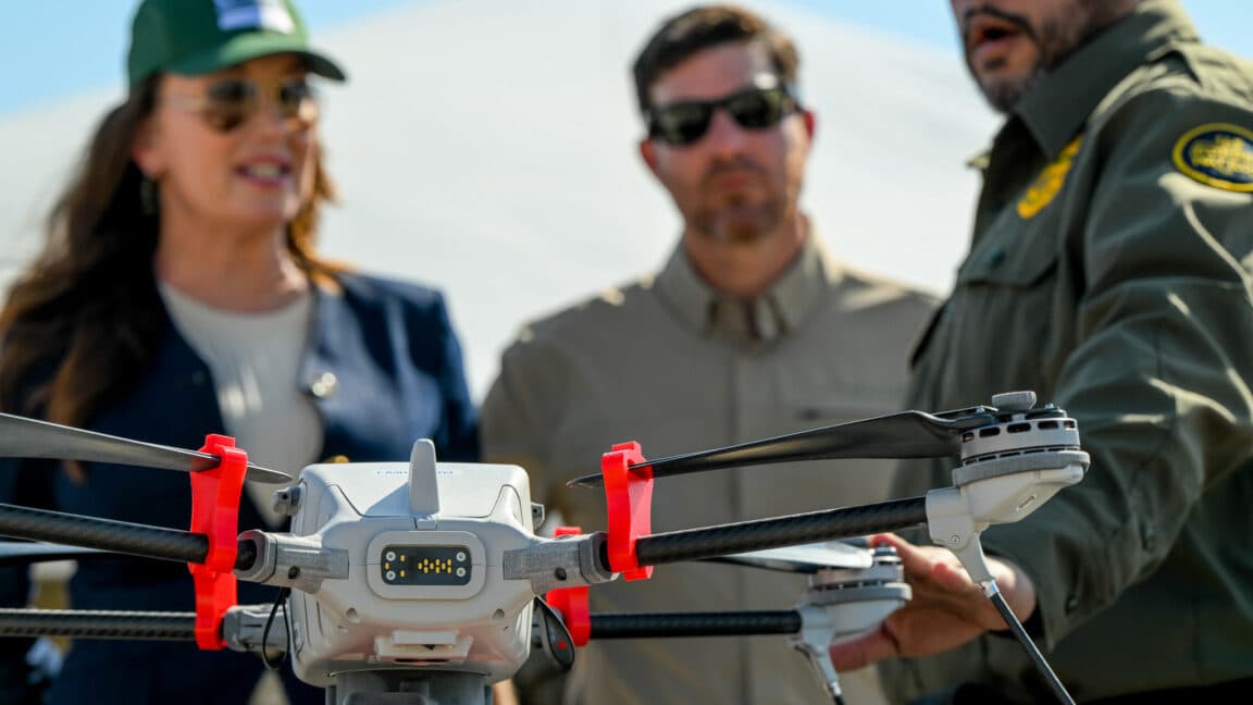 US Agriculture Secretary Brooke Rollins watches a Customs and Border Protection officer talk about a quadcopter drone sitting in the foreground. The CBP drones have been retasked to help USDA survey animals for signs of screwworm infestation.