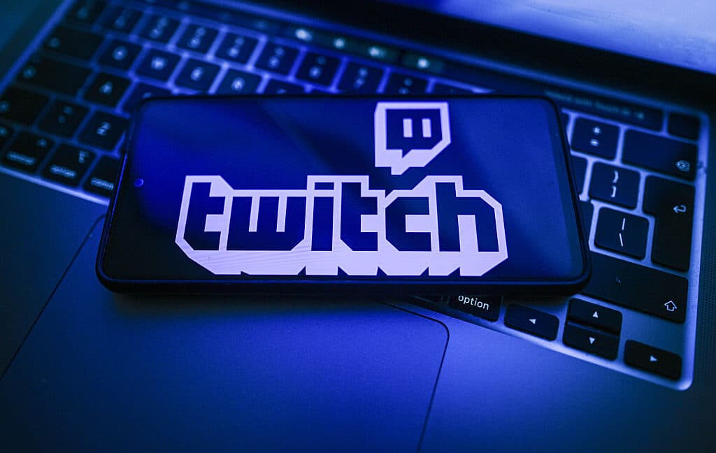In this photo illustration, a Twitch logo is seen displayed on a smartphone on the top of a laptop.
