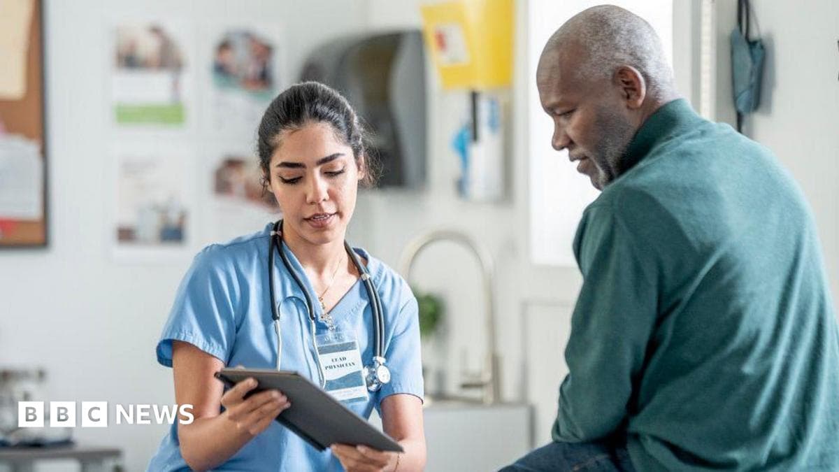 A nurse in blue scrubs with a stethoscope consults with a Black patient in a clinic, using a tablet. Warm, professional healthcare scene highlighting patient care and medical teamwork.