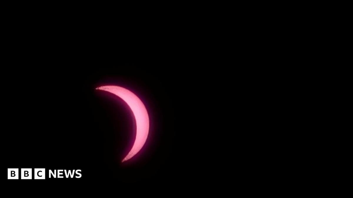 A view of the sun, which appears pink in colour, and is partially covered by the moon.