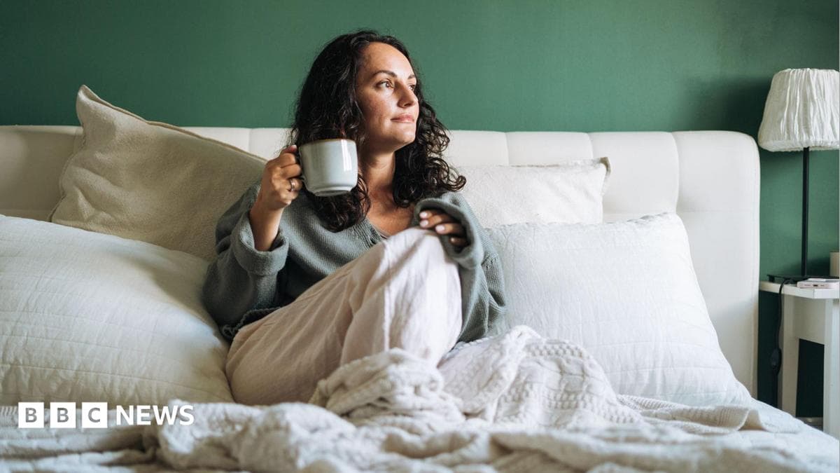A woman in bed drinking a cup of tea