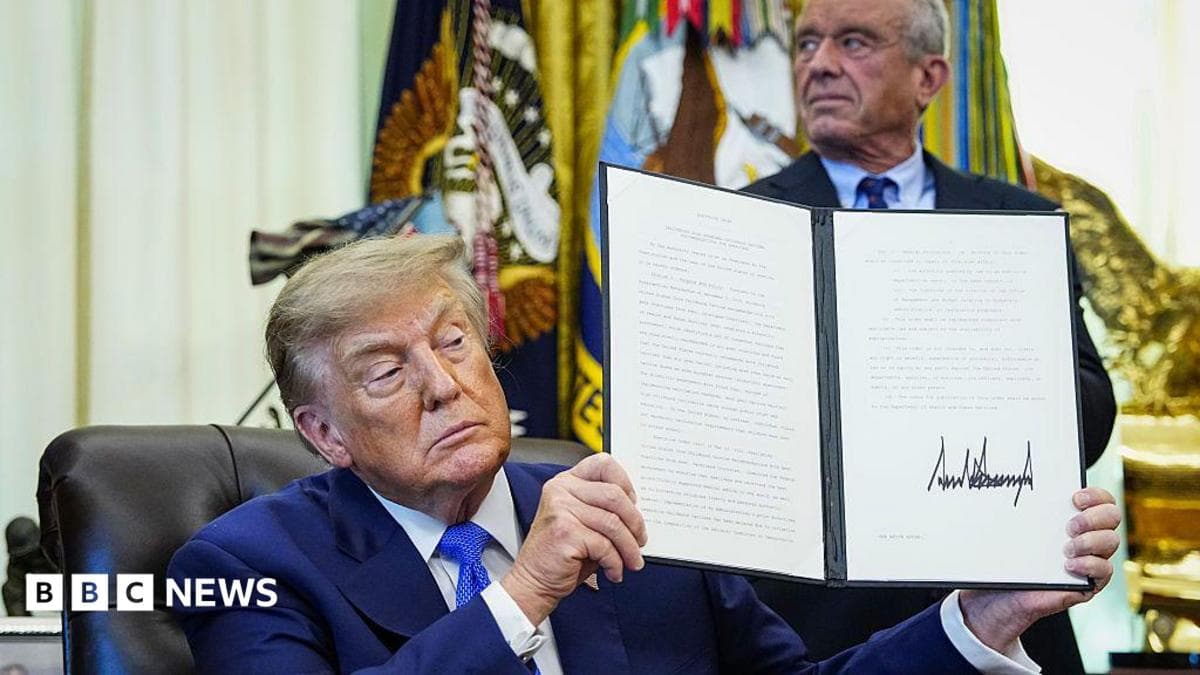US President Donald Trump holds up an executive order he signed that aims to change childhood vaccine administration