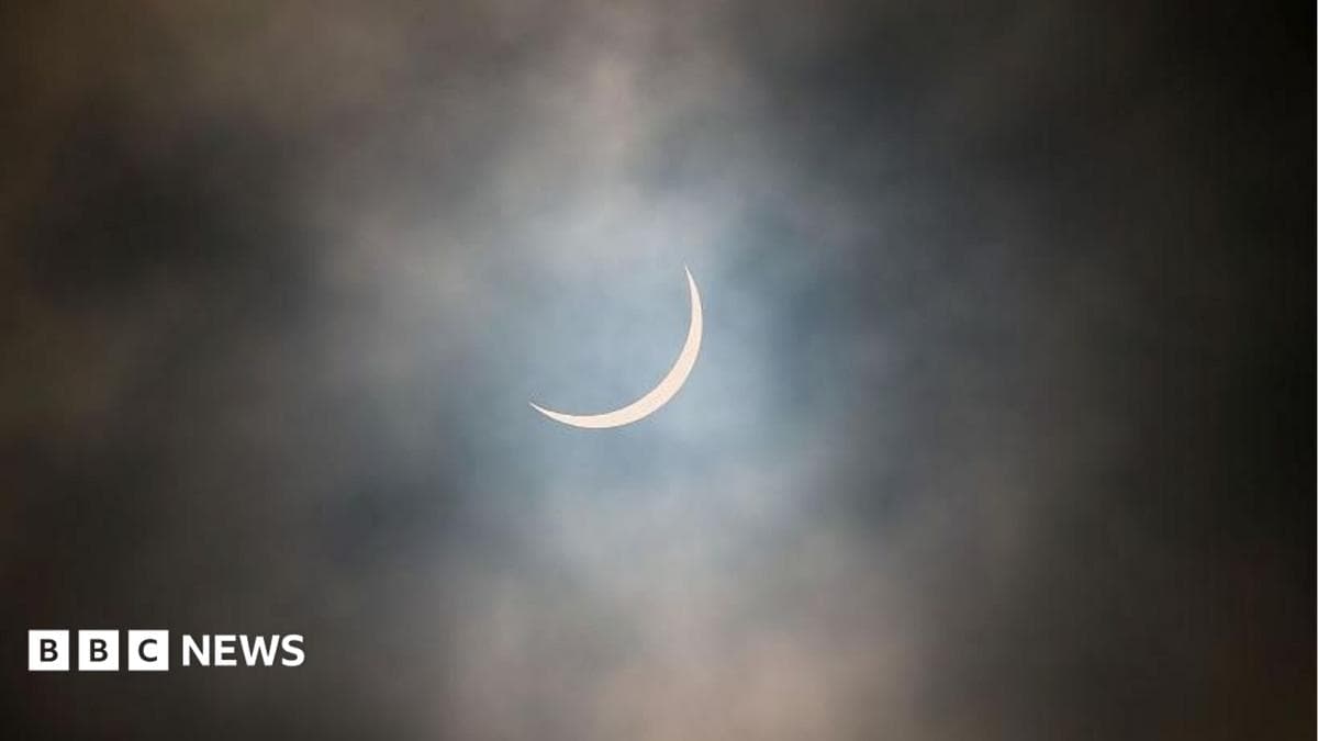 The sun is pictured during a partial solar eclipse. The sky is dark and cloudy. The sun is a thin arc in the sky. This was the partial solar eclipse seen over Glasgow in March 2015
