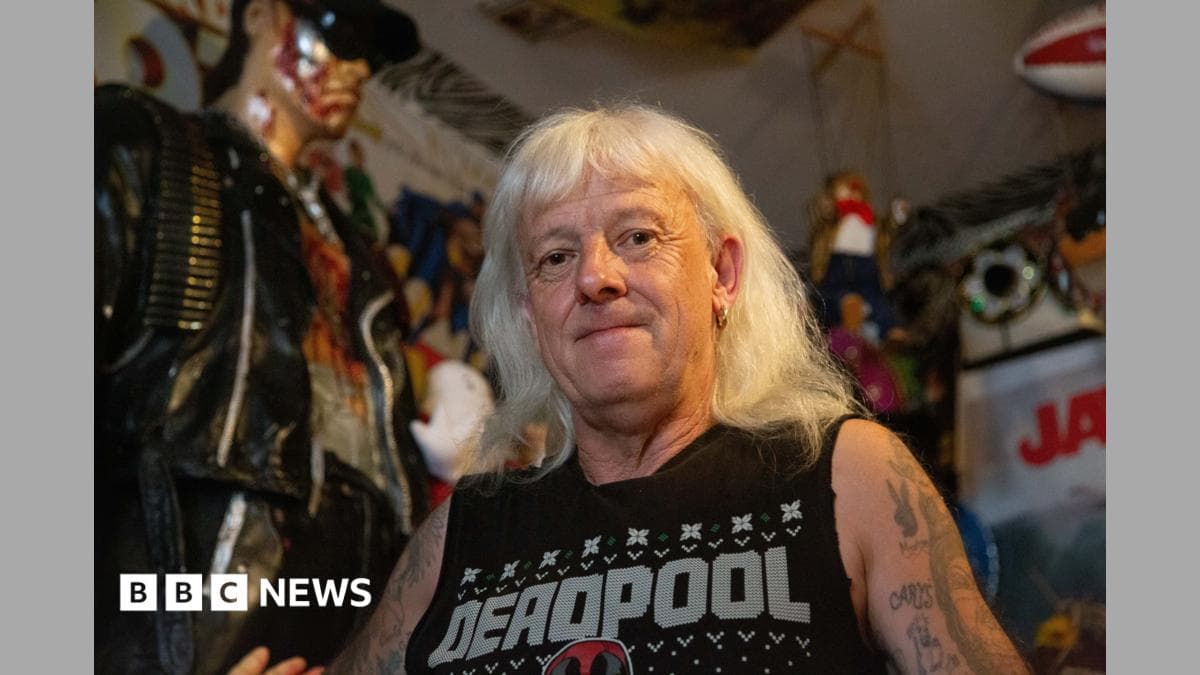 Man with white hair standing next to a 6ft Terminator