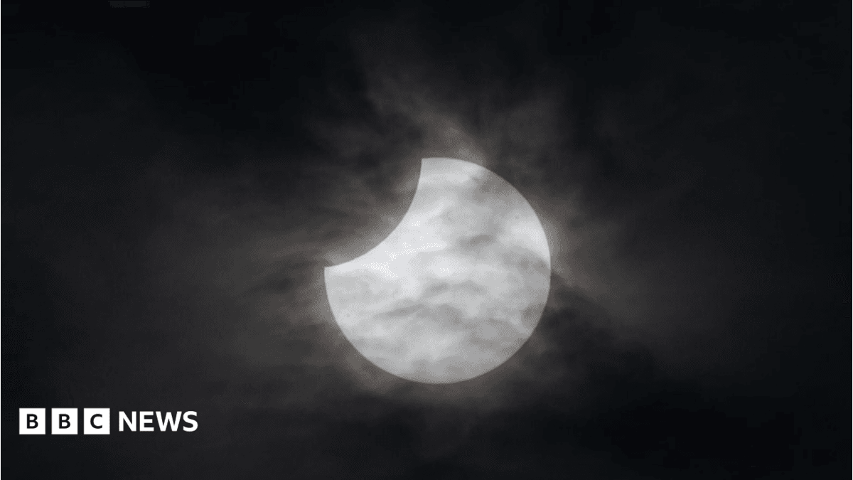 A partial solar eclipse, the sky is black and the moon is beginning to cover the sun