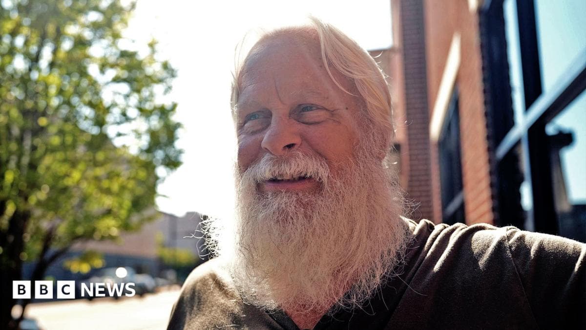 David Carter sports a full white beard - which helps him play Santa at Christmas - as he stands on a main street in downtown Kingstport