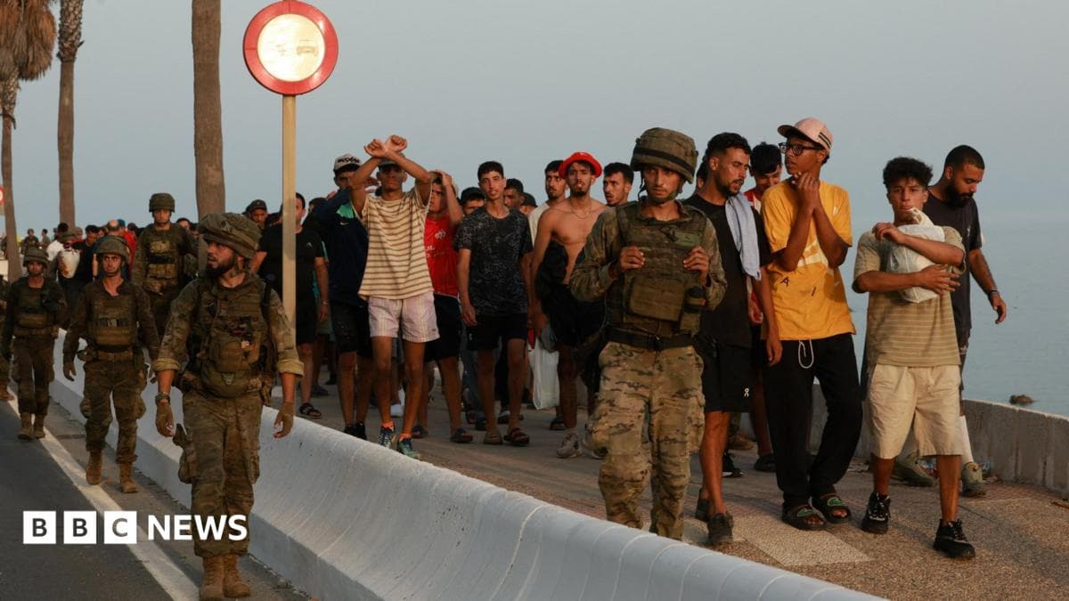 Members of the military escort migrants in Ceuta, Spain, following recent mass crossings of migrants on foot and by sea from Morocco into Spanish territory.