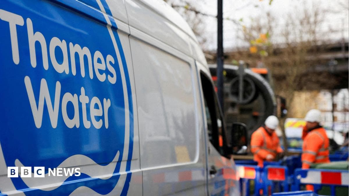 A shot of a Thames Water van. In the background there are two men wearing hi-vis clothing and hard hats and standing in an area that is boarded off by blue fences.