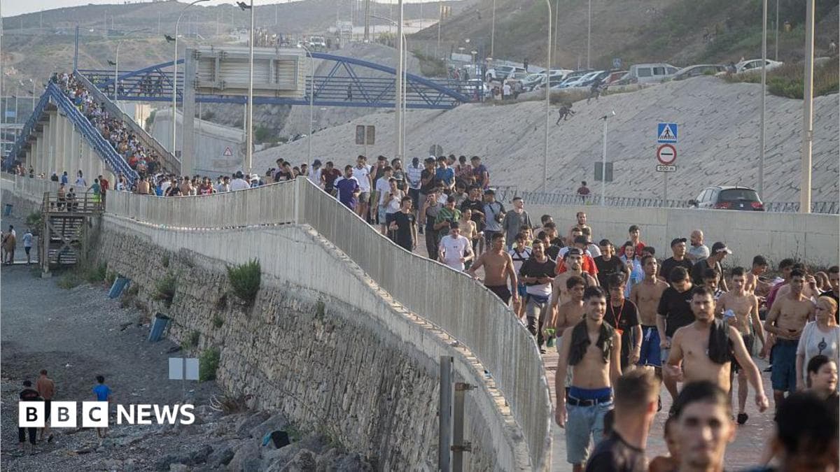 Dozens of migrants walking on a coastal path