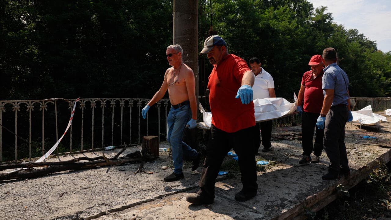 Men carry a body in a plastic bag of a person killed during Russian ballistic missile and drone strikes at a railway station in the Kyiv region on August 5, 2026.